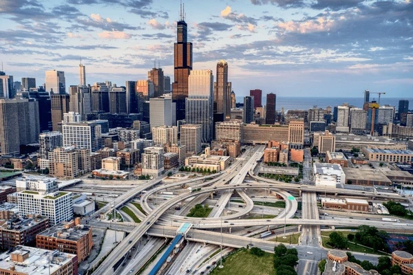 Aerial view of the Chicago skyline and a busy expressway interchange, with Willis Tower at the center